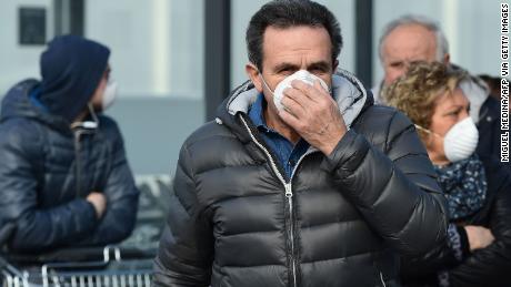 Residents wearing respiratory mask wait to be given access to shop in a supermarket in small groups of forty people on February 23, 2020 in the small Italian town of Casalpusterlengo, under the shadow of a new coronavirus outbreak, as Italy took drastic containment steps as worldwide fears over the epidemic spiralled. (Photo by Miguel MEDINA / AFP) (Photo by MIGUEL MEDINA/AFP via Getty Images)