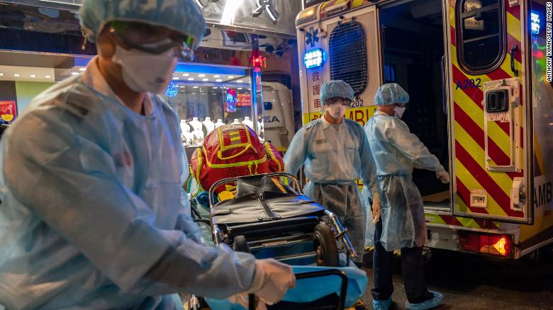Paramedics wearing personal protective equipment carry a stretcher from an ambulance at North Point district in Hong Kong.