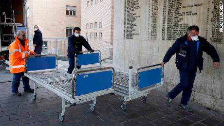 FILE - In this Friday, Feb. 21, 2020, file photo, personnel carry new beds inside a hospital of Codogno, near Lodi in Northern Italy. Health officials reported the country's first cases of contagion of COVID-19 in people who had not been in China. Italy saw cases of the new virus more than quadruple in a day as it grapples with infections in a northern region that apparently have spread through a hospital and a cafe. (AP Photo/Luca Bruno)