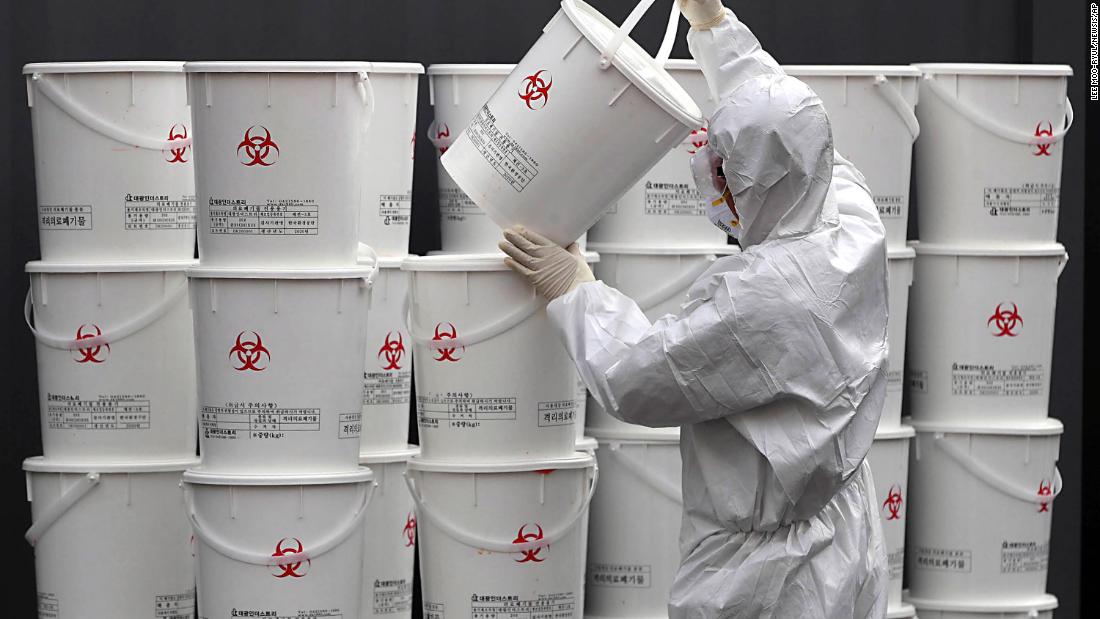 A worker in Daegu, South Korea, stacks plastic buckets containing medical waste from coronavirus patients.