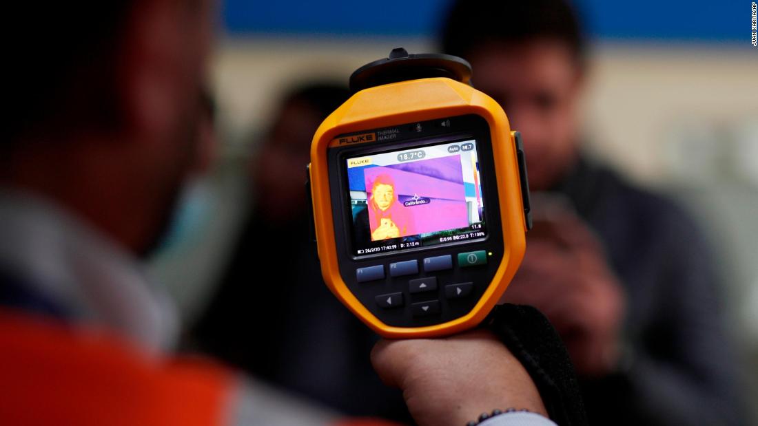 An airport employee scans people&#39;s body temperatures in Bolivia on February 26. Brazil reported its first case of the coronavirus that day -- the first case in Latin America. Other nearby countries are now attempting to block the possible spread of the virus.