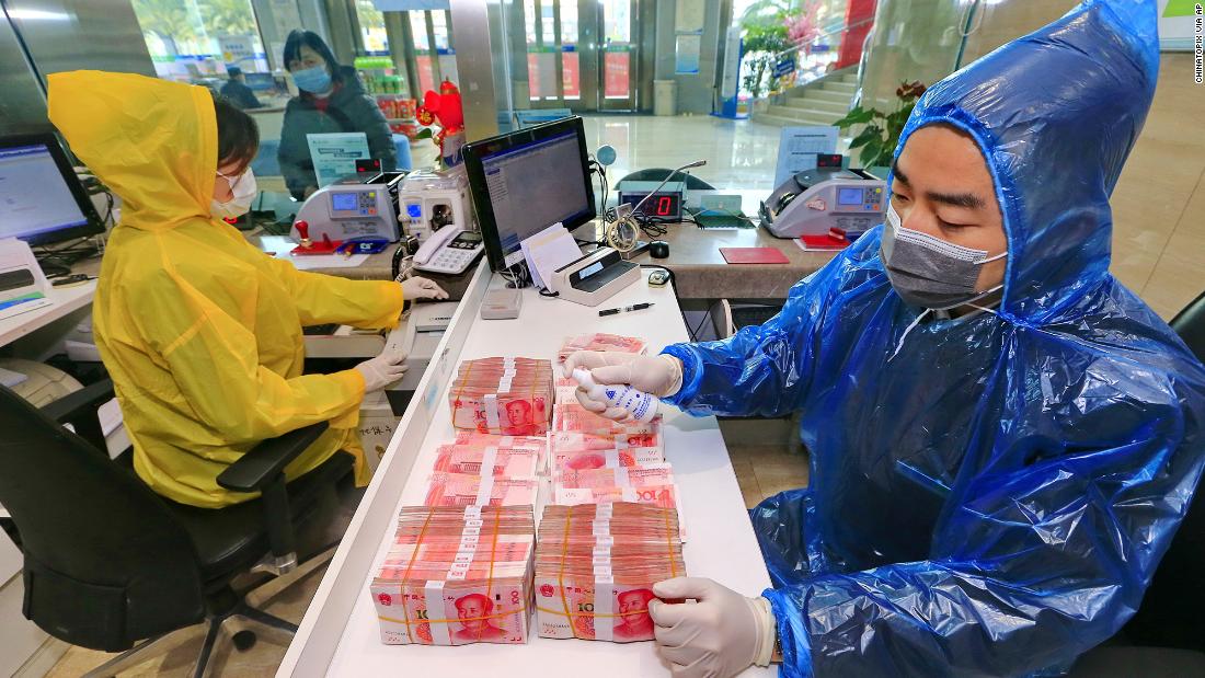 A bank clerk disinfects banknotes in China's Sichuan province on February 26, 2020.