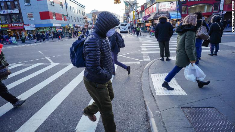 People wear protective masks to fend off the coronavirus, while street vendors pedal hand sanitizer and other disinfecting products in Queens, New York.