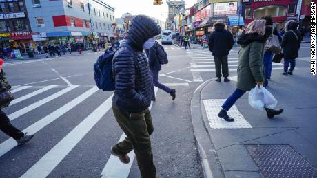 People wear protective masks to fend off the coronavirus, while street vendors peddlel hand sanitizer and other disinfecting products in Queens, New York.