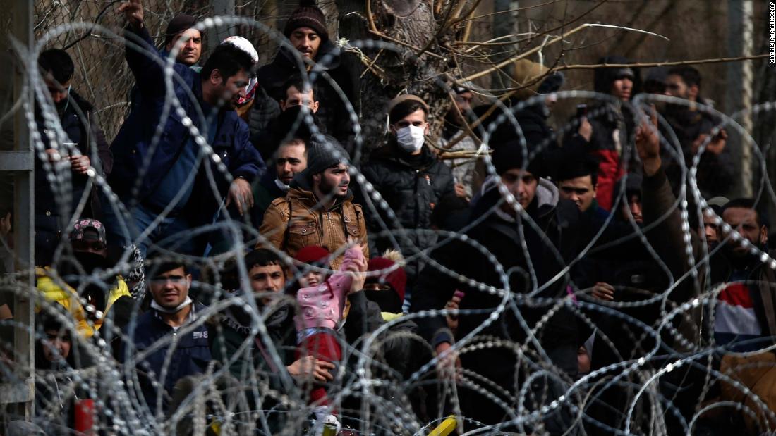 Migrants stand behind a fence at Turkey&#39;s border with Greece on Monday, March 2.