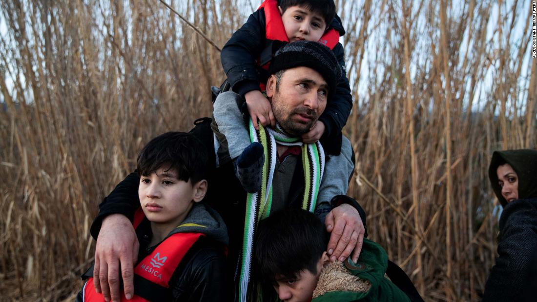 A man holds his three sons as migrants arrive on a dinghy March 2 near the Greek village of Skala Sikamias. They had crossed from Turkey to the island of Lesbos.