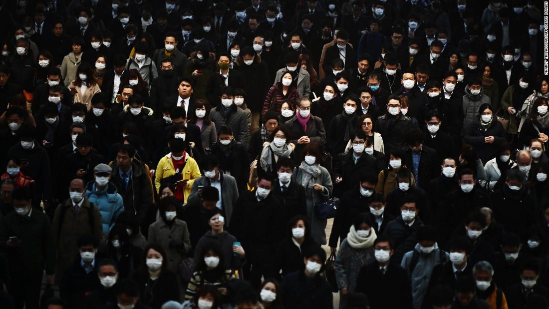 Commuters wearing masks make their way to work during morning rush hour at the Shinagawa train station in Tokyo.