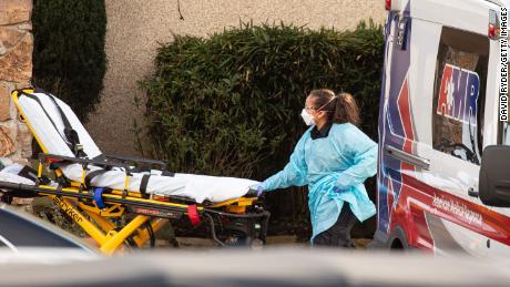 A healthcare worker prepares to transport a patient on a stretcher into an ambulance at Life Care Center of Kirkland on February 29.