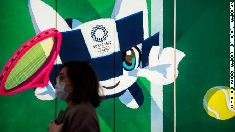 TOKYO, JAPAN - FEBRUARY 26: A pedestrian wearing a face mask walks past a display with an illustration of the 2020 Tokyo Olympic and Paralympic Games mascot character Miraitowa on February 26, 2020 in Tokyo, Japan. Concerns that the Tokyo Olympics may be postponed or cancelled are increasing as Japan confirms 862 cases of Coronavirus (COVID-19) and as some professional sporting contests are being called off or rescheduled and some major Japanese corporations ask for people to work from home. (Photo by Tomohiro Ohsumi/Getty Images)