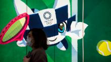 TOKYO, JAPAN - FEBRUARY 26: A pedestrian wearing a face mask walks past a display with an illustration of the 2020 Tokyo Olympic and Paralympic Games mascot character Miraitowa on February 26, 2020 in Tokyo, Japan. Concerns that the Tokyo Olympics may be postponed or cancelled are increasing as Japan confirms 862 cases of Coronavirus (COVID-19) and as some professional sporting contests are being called off or rescheduled and some major Japanese corporations ask for people to work from home. (Photo by Tomohiro Ohsumi/Getty Images)