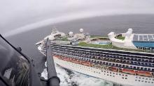 In this image from video, provided by the California National Guard, a helicopter carrying airmen with the 129th Rescue Wing flies over the Grand Princess cruise ship off the coast of California Thursday, March 5, 2020. Scrambling to keep the coronavirus at bay, officials ordered a cruise ship with 3,500 people aboard to stay back from the California coast Thursday until passengers and crew can be tested, after a traveler from its previous voyage died of the disease and at least two others became infected. Airmen lowered test kits onto the 951-foot (290-meter) Grand Princess by rope as the vessel lay at anchor off Northern California, and authorities said the results would be available on Friday. Princess Cruise Lines said fewer than 100 people aboard had been identified for testing. 