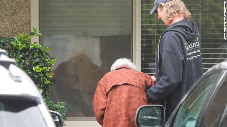 Charlie Campbell  takes his mom Dorothy Campbell, 88, to see her husband Gene Campbell, 89, through his room window at the Life Care Center nursing home in Kirkland, Washington. 