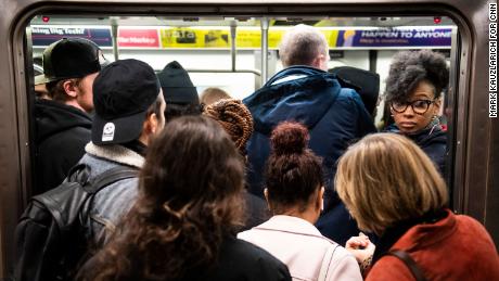 People board a crowded subway train in the New York City.