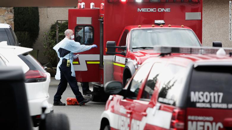 Ambulance staff prepare to transport a patient from the Life Care Center nursing home where some patients have died from coronavirus in Kirkland, Washington.