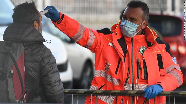 A health staff checks the body temperature of a man arriving at the stadium.