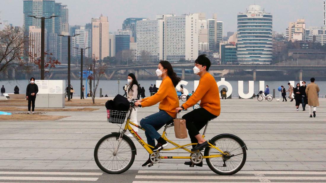 A couple rides a bicycle at a park in Seoul, South Korea, on March 7, 2020.