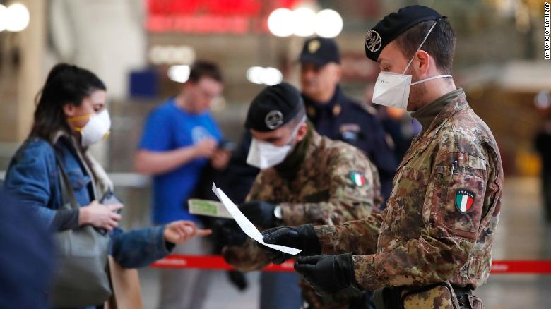 Police officers and soldiers check passengers leaving from Milan's main train station after travel was canceled except for work and health reasons.