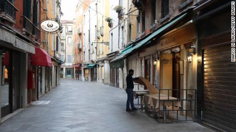VENICE, ITALY - MARCH 9: A waiter sets a table in a restaurant on an empty street on March 9, 2020 in Venice, Italy. Prime Minister Giuseppe Conte announced a &quot;national emergency&quot; due to the coronavirus outbreak and imposed quarantines on the Lombardy and Veneto regions, which contain roughly a quarter of the country&#39;s population. Italy has the highest number of cases and fatalities in Europe. The movements in and out are allowed only for work reasons, health reasons proven by a medical certificate.The justifications for the movements needs to be certified with a self-declaration by filling in forms provided by the police forces in charge of the checks.(Photo by Marco Di Lauro/Getty Images)