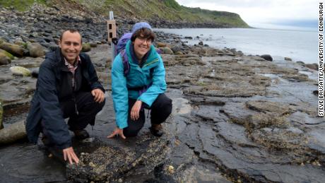 Steve Brusatte and Paige dePolo pose with fossil dinosaur tracks on the Isle of Skye.