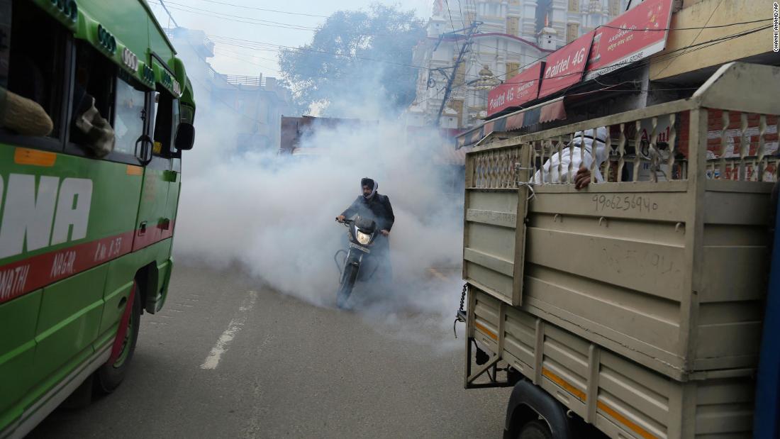 A motorcyclist drives through disinfectant sprayed in Jammu, India, on March 13, 2020.