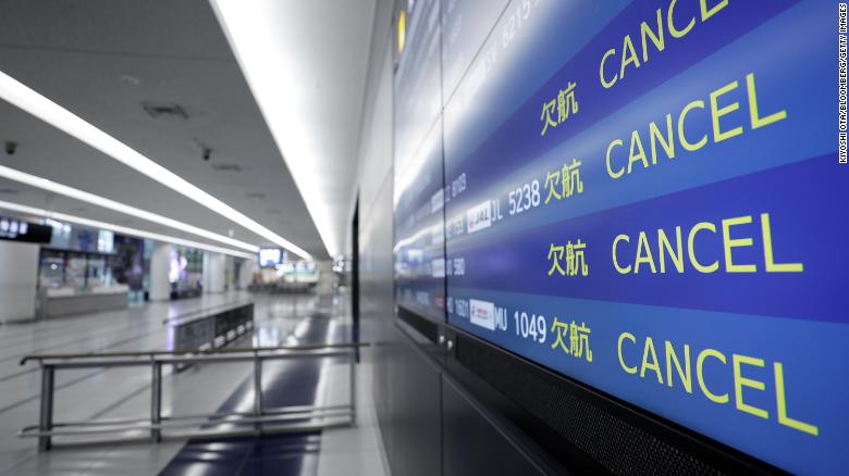 A flight arrival information board displays cancelled flights at an airport in Japan.