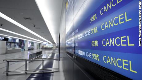 A flight arrival information board displays cancelled flights at an airport in Japan.