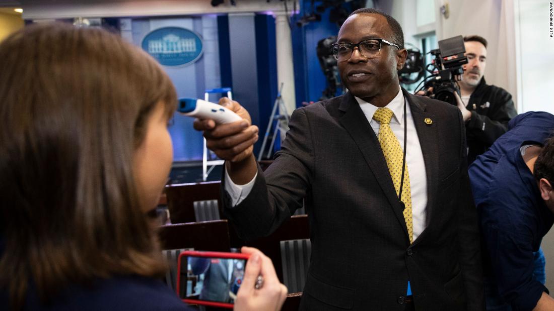 A member of the White House physician&#39;s office takes a media member&#39;s temperature in the White House briefing room. It was ahead of a news conference with President Donald Trump and Vice President Mike Pence.