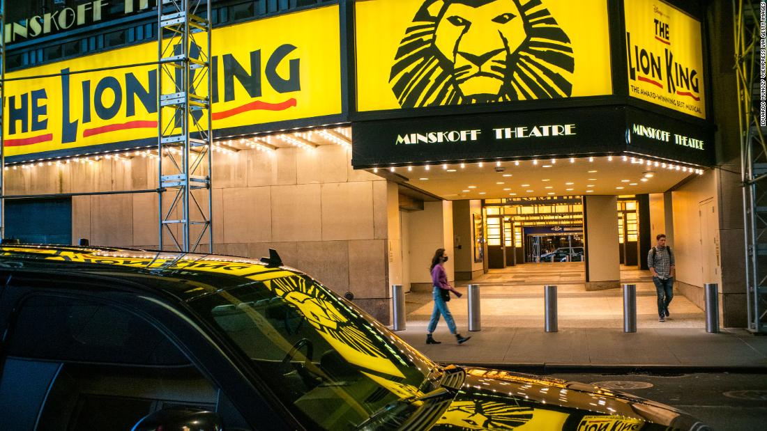 People walk past a closed Broadway theater after New York canceled all gatherings over 500 people.