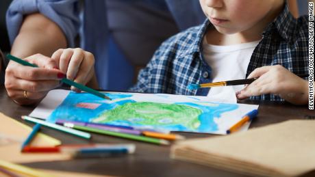 Portrait of cute little boy painting picture with mom helping him, copy space