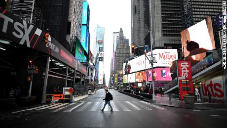 A tourist crosses the 7th Avenue at Times Square on March 13, 2020 in New York City. (Photo by Johannes Eisele/AFP/Getty Images)