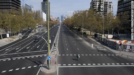 A woman crosses the usually busy La Castellana avenue in Madrid on March 15, 2020.