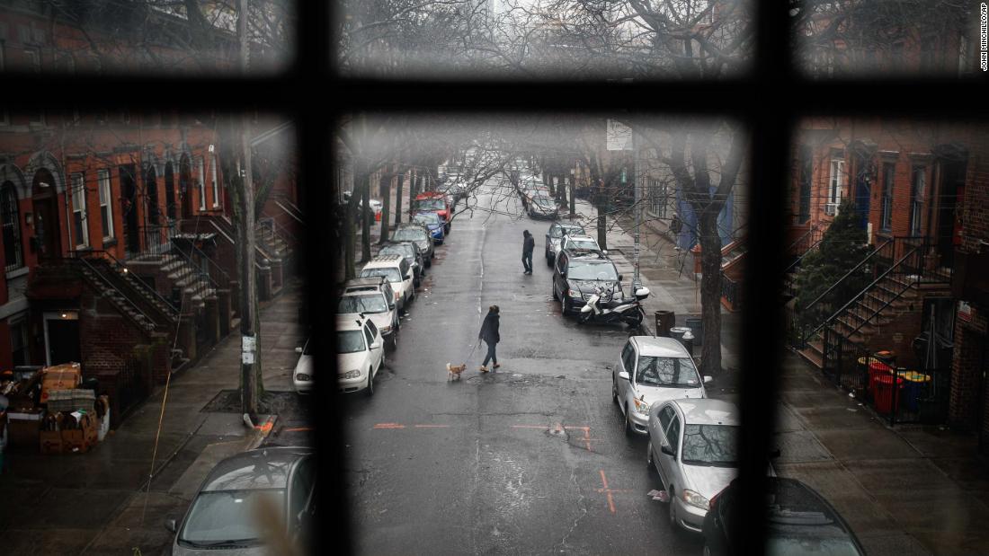 A pedestrian walks a dog through a quiet street in New York on March 17, 2020.