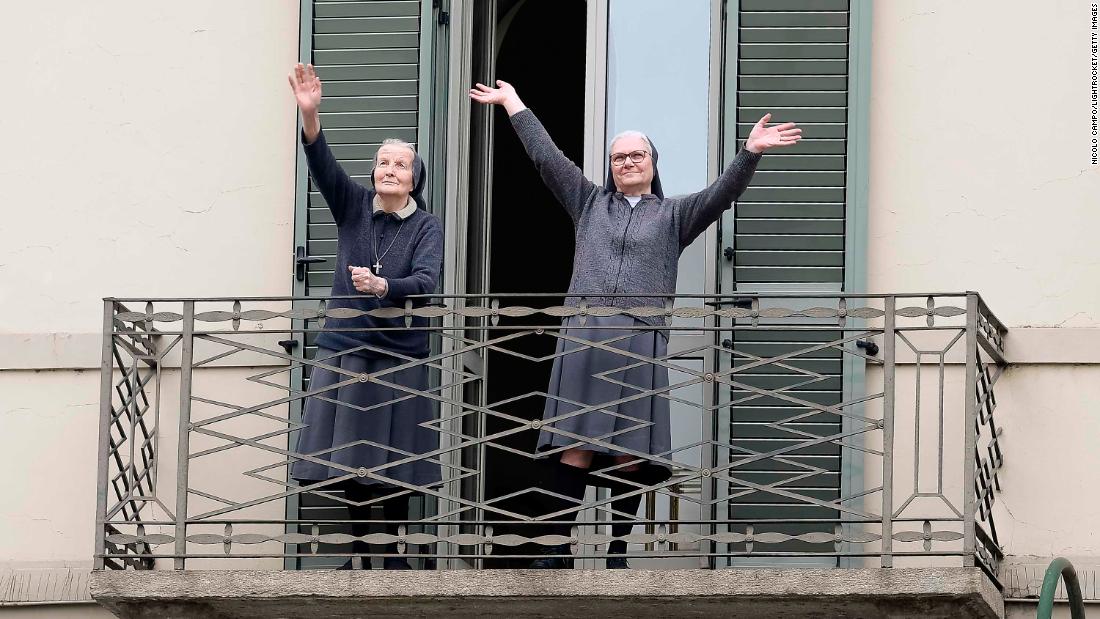Two nuns greet neighbors from their balcony in Turin, Italy, on March 15, 2020.