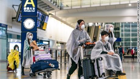 Travellers wearing protective equipment enter the arrival hall at the Hong Kong International Airport on March 17, 2020 in Hong Kong.