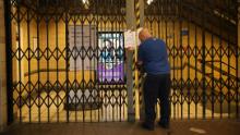 A worker closes the gates of Barbican underground station as public transport services in London are reduced.