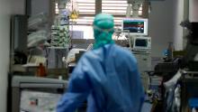 In this March 16, 2020, photo, a doctor watches a coronavirus patient under treatment in the intensive care unit of the Brescia hospital, Italy. Hospitals in northern Italy are struggling to make room for the onslaught of coronavirus patients. (AP Photo/Luca Bruno)