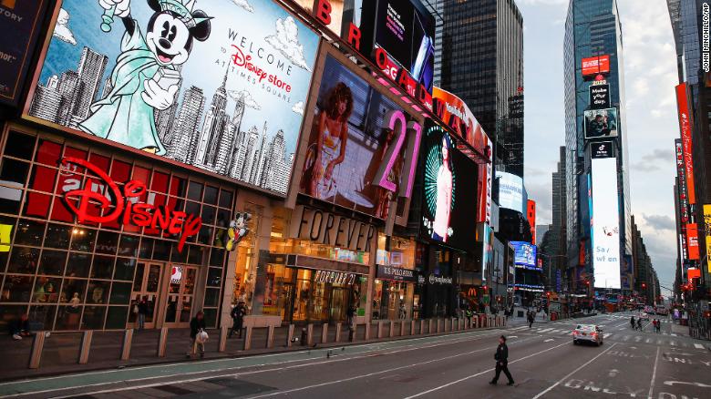 A police officer walks across an empty 7th Avenue in a sparsely populated Times Square due to Covid-19 concerns on Friday, March 20, 2020, in New York.