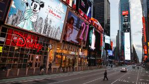 A police officer walks across an empty 7th Avenue in a sparsely populated Times Square due to COVID-19 concerns, Friday, March 20, 2020, in New York. New York Gov. Andrew Cuomo is ordering all workers in non-essential businesses to stay home and banning gatherings statewide. "Only essential businesses can have workers commuting to the job or on the job," Cuomo said of an executive order he will sign Friday. Nonessential gatherings of individuals of any size or for any reason are canceled or postponed. (AP Photo/John Minchillo)