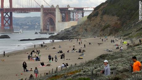 People line Baker Beach near the Golden Gate Bridge on Sunday, March 22, 2020, in San Francisco. Some 40 million Californians are coping with their first weekend under a statewide order requiring them to stay at home to help curb the spread of the coronavirus.