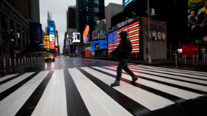 A man crosses the street in a nearly empty Times Square, which is usually very crowded on a weekday morning, Monday, March 23, 2020 in New York. Gov. Andrew Cuomo has ordered most New Yorkers to stay home from work to slow the coronavirus pandemic. (AP Photo/Mark Lennihan)