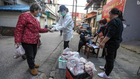 In this March 18, 2020 photo, people buy pork at the entrance gate of a closed residential community in Wuhan in central China&#39;s Hubei Province. Last month, Wuhan was overwhelmed with thousands of new cases of coronavirus each day. But in a dramatic development that underscores just how much the outbreak has pivoted toward Europe and the United States, Chinese authorities said Thursday that the city and its surrounding province had no new cases to report. The virus causes only mild or moderate symptoms, such as fever and cough, for most people, but severe illness is more likely in the elderly and people with existing health problems. (Chinatopix via AP)