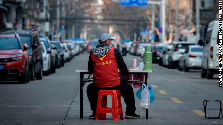 A volunteer guards a temporary wall blocking a road in Wuhan on March 12.