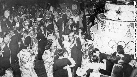 At a Christmas party in Tokyo, on the right is a large cake with the inscription 1940 XII Olympiad Tokyo to celebrate the upcoming Olympics in Japan.