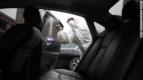 A worker wears protective clothing as he disinfects a car for Chinese ride hailing company Didi in Beijing in February. 