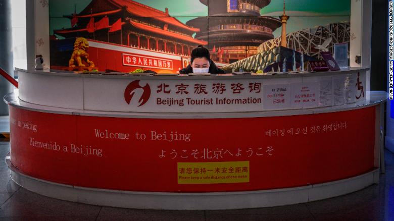 A Chinese tourist information clerk wears a protective mask as she works in a kiosk in the arrivals area at Beijing Capital International Airport on March 24, 2020 in Beijing, China.