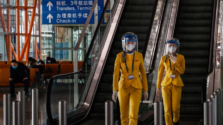 Staff wear protective masks and visors as they walk in the arrivals area at Beijing Capital International Airport on March 24.