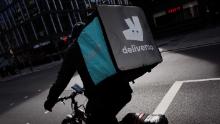 A Deliveroo courier cyclist waits at traffic lights on a near-deserted Tottenham Court Road in London, England, on March 21, 2020. Much of central London was virtually empty today, a day after British Prime Minister Boris Johnson ordered the closure of all pubs, bars, cafes and restaurants around the country. The move represents a toughening of measures to enforce the &#39;social distancing&#39; that is being urged on citizens to reduce the growth of covid-19 coronavirus infections. Nightclubs, theatres, cinemas, gyms and leisure centres were also ordered closed. Some shops in the centre of capital remained open today, albeit mostly deserted of customers; many retailers however have temporarily closed their doors until the crisis abates. (Photo by David Cliff/NurPhoto via Getty Images)