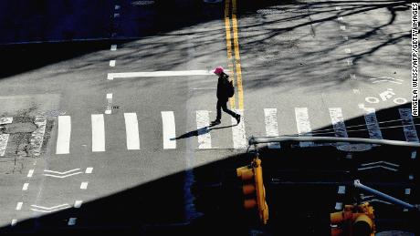 A person crosses the street on March 27, 2020 in New York City. - The US now has more COVID-19 infections than any other country, and a record number of newly unemployed people, as the coronavirus crisis deepens around the world. (Photo by Angela Weiss/AFP/Getty Images)