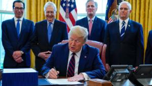 President Donald Trump signs the coronavirus stimulus relief package in the Oval Office at the White House, Friday, March 27, 2020, in Washington, as Treasury Secretary Steven Mnuchin, Senate Majority Leader Mitch McConnell, R-Ky., House Minority Leader Kevin McCarty, R-Calif., and Vice President Mike Pence watch. 