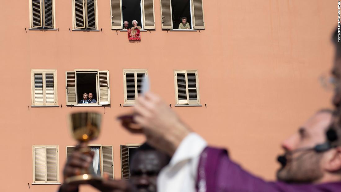 People listen from their homes as priests conduct Sunday mass from a church roof in Rome on March 29, 2020.